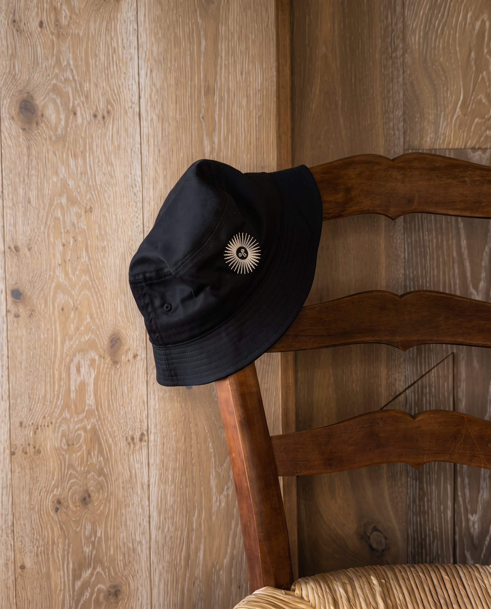 The black piluso resting on a rush-seat chair against a pale oak wall.