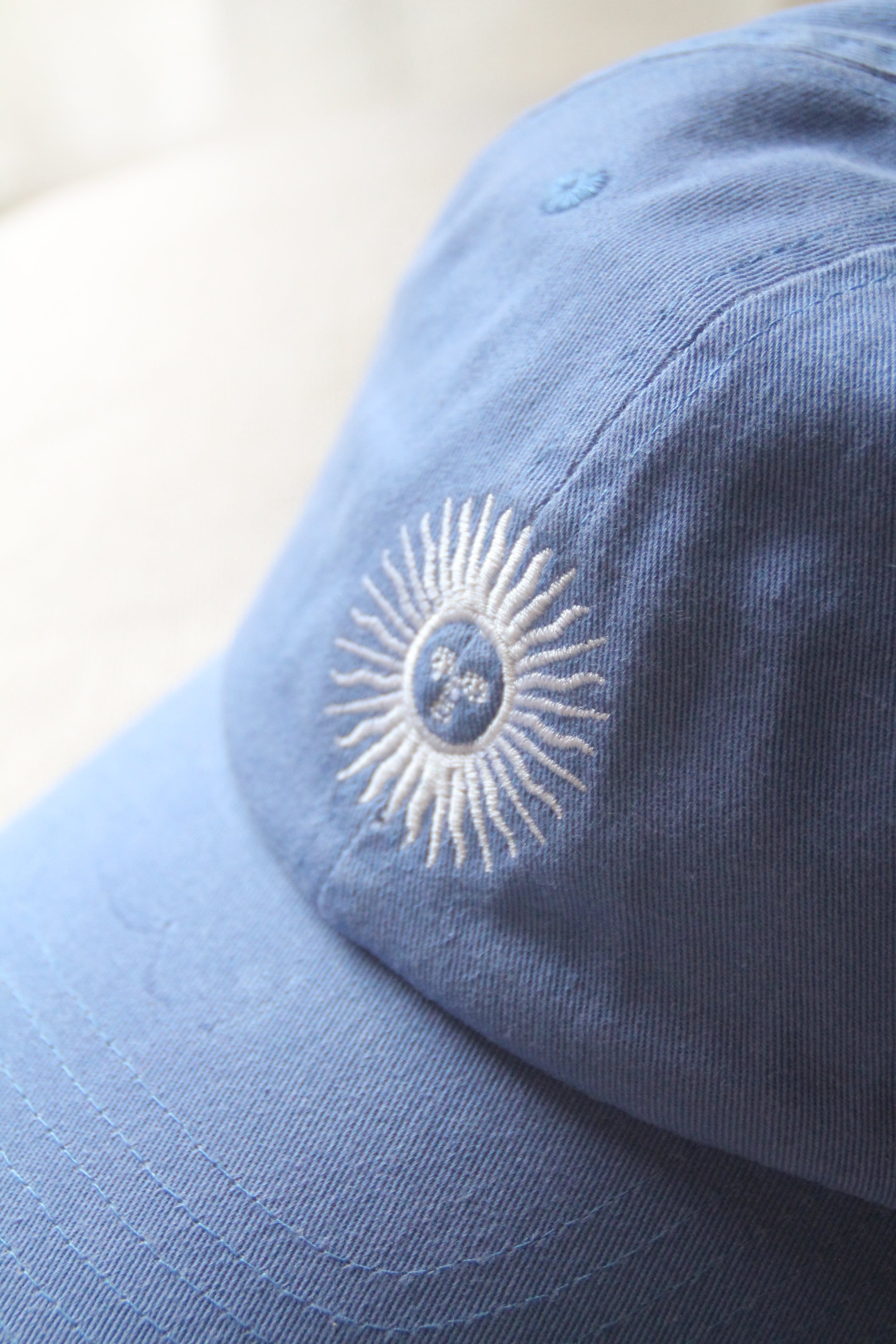 close-up of the white sol de mayo embroidery stitched on light blue cotton twill